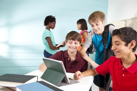 students in classroom working together around a tablet